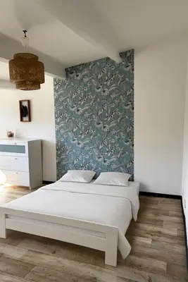 a bedroom with a white bed and a wall mural at Maisonnette rénovée en campagne in Velleron