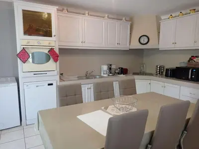 a kitchen with white cabinets and a table with chairs at maison piscine privée Robion Luberon idéal famille in Robion en Luberon