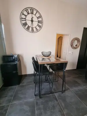 a table and chairs in a room with a clock on the wall at Ma Charmante Maison En Provence in Lançon-Provence