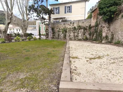 a stone wall next to a field of grass at Appartement fontaine de Vaucluse in Fontaine-de-Vaucluse