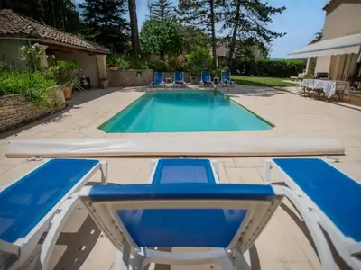 a swimming pool with two blue lounge chairs and a swimming pool at Le grand Liodrey in Céreste