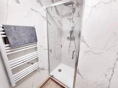 a shower in a bathroom with white marble walls at Le Forbin by La Familia in Aix-en-Provence