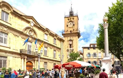 a crowd of people walking in front of a building with a clock tower at le Signoret in Aix-en-Provence