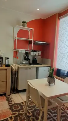 a kitchen with red walls and a table with chairs at Studio rénové maison de village du Luberon in Villelaure