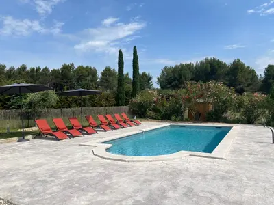 a swimming pool with lounge chairs and an umbrella at Proche Roussillon, La villa rouge Luberon, piscine chauffée, climatisation et vue Luberon in Gargas