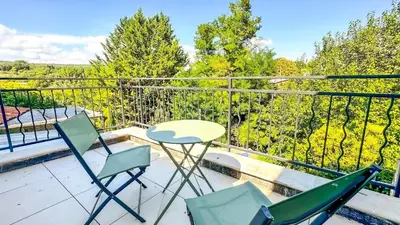 a patio with two chairs and a table on a balcony at Les Iris in Céreste