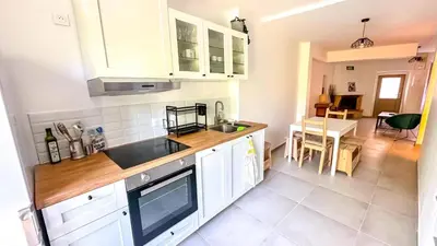 a kitchen with white cabinets and a dining room at Les Iris in Céreste