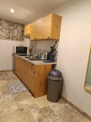 a kitchen with wooden cabinets and a trash can at Écrin de nature sous les pins in Aurons