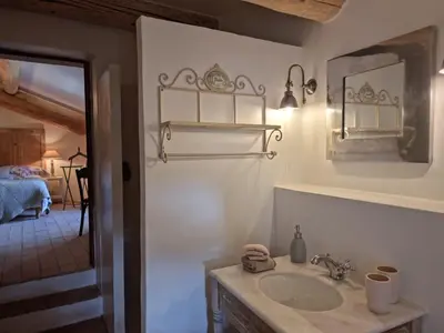 a bathroom with a sink and a mirror and a bedroom at Mas Cerisiers in Saint-Martin-de-Castillon
