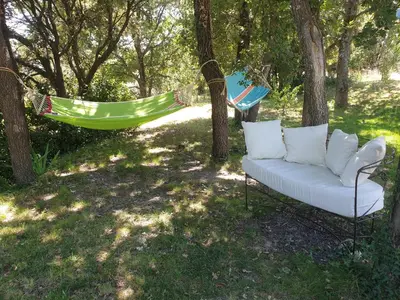 a white couch sitting in a yard with a hammock at Gîtes L'HERMITAGE in La Tour-dʼAigues