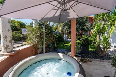 a hot tub with an umbrella in a yard at Maison Tiki Village Aix centre in Aix-en-Provence