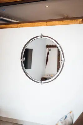 a round mirror hanging on a wall at La Remise en Forme in Entraigues-sur-la-Sorgue