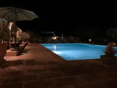 a swimming pool at night with an umbrella at Chambre d'hôtes chez Maguy B-Villa Makeire in Gordes