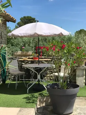 a table with an umbrella in a garden at Chambre d'hôtes chez Maguy B-Villa Makeire in Gordes