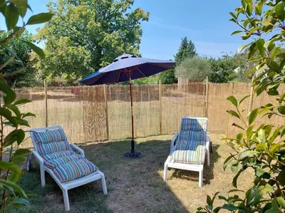 two chairs and an umbrella in a yard at Maison de César in Saint-Saturnin-les-Apt