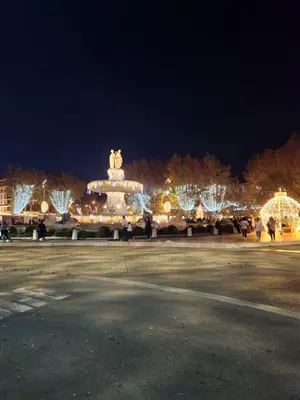 a lit up street with people walking around at night at Le Beffroi de Gaston Climatisé in Aix-en-Provence