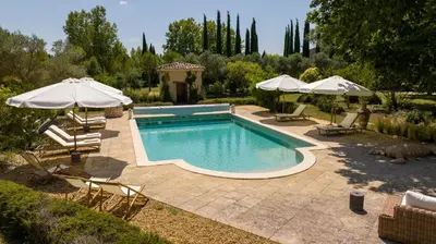a pool with chairs and umbrellas in a yard at Le Domaine du Printemps in Monteux