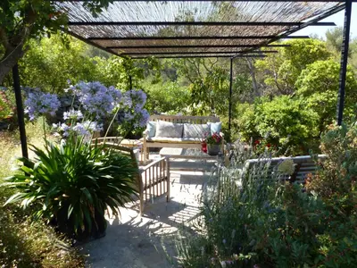 a garden with a pergola and a bench and flowers at Lou Pantai, Bed and Breakfast, Delux Bedroom with AC in Aix-en-Provence