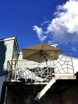 a balcony with an umbrella on top of a building at Entre Ventoux et Luberon, appartement dans maison. in Malemort-du-Comtat