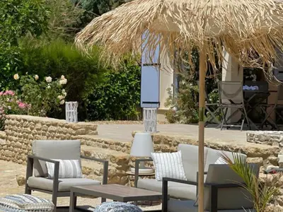 a patio with chairs and tables and a straw umbrella at La Roque in La Roque-sur-Pernes