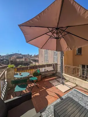 a patio with an umbrella and a table and chairs at UNE TERRASSE SUR LES TOITS in Aix-en-Provence