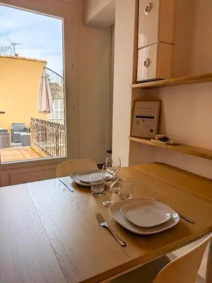 a wooden table with plates and glasses and a window at UNE TERRASSE SUR LES TOITS in Aix-en-Provence
