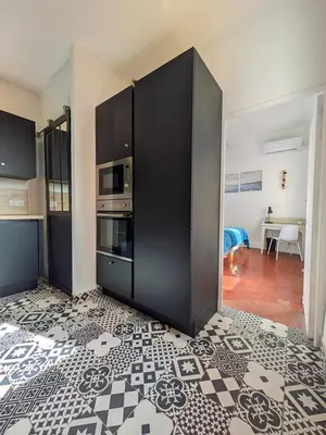 a kitchen with black cabinets and a tile floor at UNE TERRASSE SUR LES TOITS in Aix-en-Provence