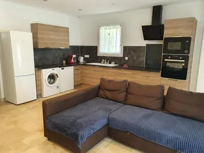 a living room with a couch and a kitchen at Petite maison en campagne in Pernes-les-Fontaines