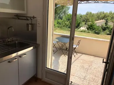 a patio with two chairs and an umbrella at Appartement dans bastide à Saint Rémy de Provence in Saint-Rémy-de-Provence