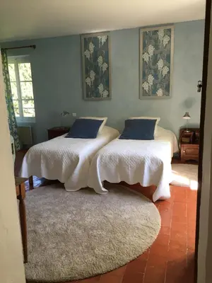 two beds in a room with white sheets and blue pillows at Domaine la Carraire in Lauris