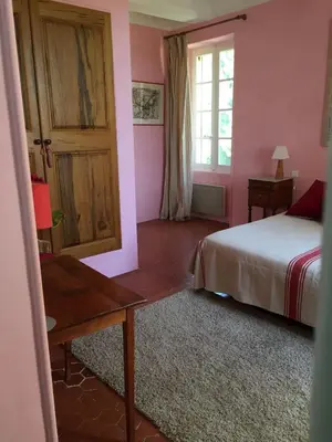 a bedroom with a bed and a table and a window at Domaine la Carraire in Lauris