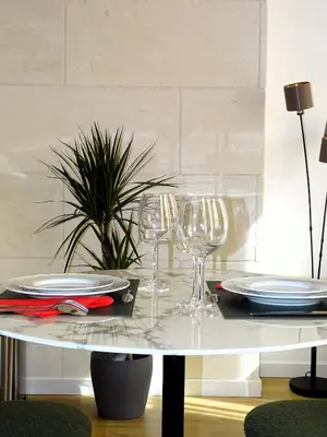 a table with wine glasses and plates on it at AUGUSTINS FOUNTAIN Studio Cosy AIX Centre Historique à 3 minutes de COURS MIRABEAU -WIFI-SMART TV-RUE CALME in Aix-en-Provence