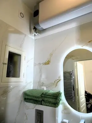 a bathroom with a mirror and green towels on a shelf at AUGUSTINS FOUNTAIN Studio Cosy AIX Centre Historique à 3 minutes de COURS MIRABEAU -WIFI-SMART TV-RUE CALME in Aix-en-Provence