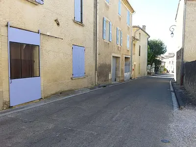 an empty street next to a building with blue doors at Les Studios proche du Mont Ventoux in Mazan