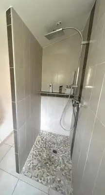 a bathroom with a shower with a stone floor at La pause en luberon in Cavaillon