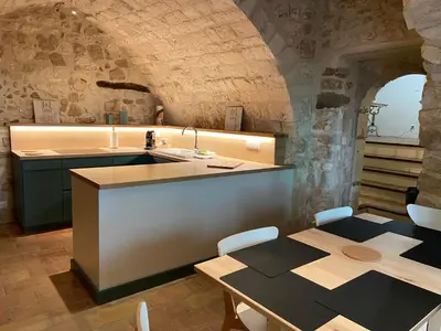 a kitchen with a counter and a table with a sink at Maison de village in Pernes-les-Fontaines