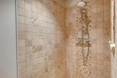 a shower in a bathroom with brown tiles at Gite neuf avec piscine Bio uv in Saint-Saturnin-les-Apt