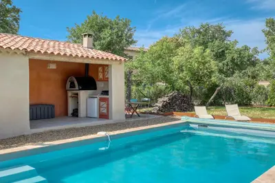 a pool with two chairs next to a house at Gite neuf avec piscine Bio uv in Saint-Saturnin-les-Apt