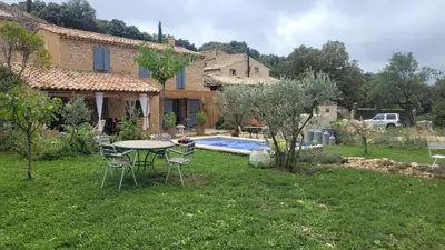 a garden with a table and chairs in front of a house at Maison de charme avec piscine in Simiane-la-Rotonde