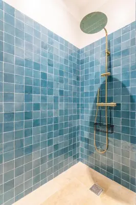 a blue tiled bathroom with a shower with a shower head at Magnifique appartement centre historique in Aix-en-Provence