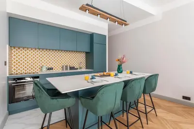 a kitchen with blue cabinets and a table with green chairs at Magnifique appartement centre historique in Aix-en-Provence