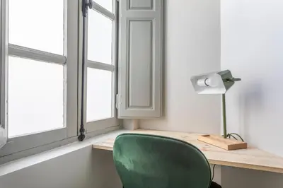 a green chair sitting next to a desk with a window at Magnifique appartement centre historique in Aix-en-Provence