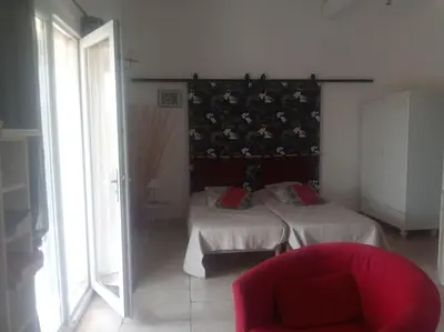 a bedroom with two beds and a red chair at Gite LE PETIT LUBERON COQUELICOT in Coustellet