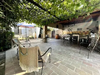 a patio with chairs and tables and an umbrella at Appartement dans Mas Provencal in Grans