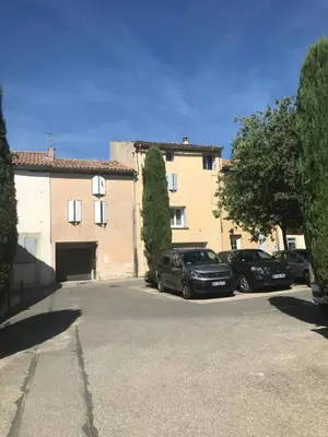 a parking lot with cars parked in front of a building at Appartement climatisé au pied du Mont Ventoux in Malemort-du-Comtat