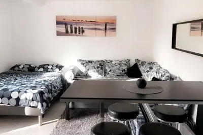 a living room with a bed and a table and stools at Studios moderne et spacieux in Morières-lès-Avignon