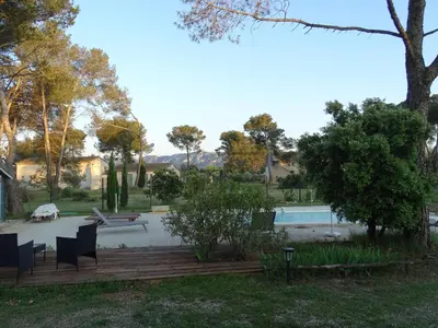 a view of a pool with chairs and trees at La Coudoulière in Saint-Rémy-de-Provence