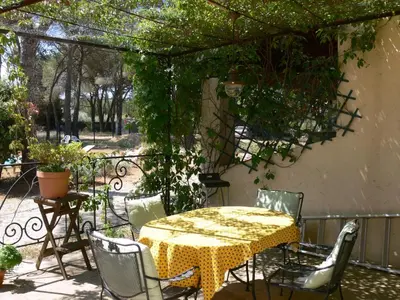 a table and chairs on a patio with a pergola at La Coudoulière in Saint-Rémy-de-Provence