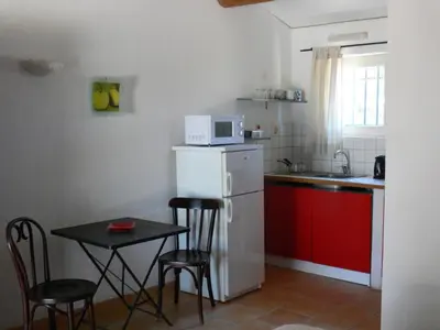 a small kitchen with a small table and a white refrigerator at La Coudoulière in Saint-Rémy-de-Provence