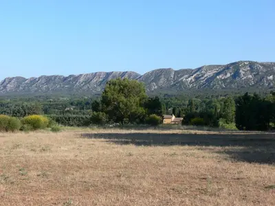a field with a house and mountains in the background at La Coudoulière in Saint-Rémy-de-Provence